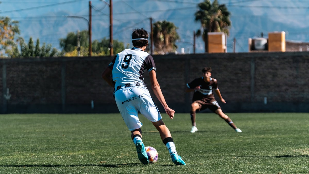Dynamic image of two soccer players in action on the field under a clear sky.